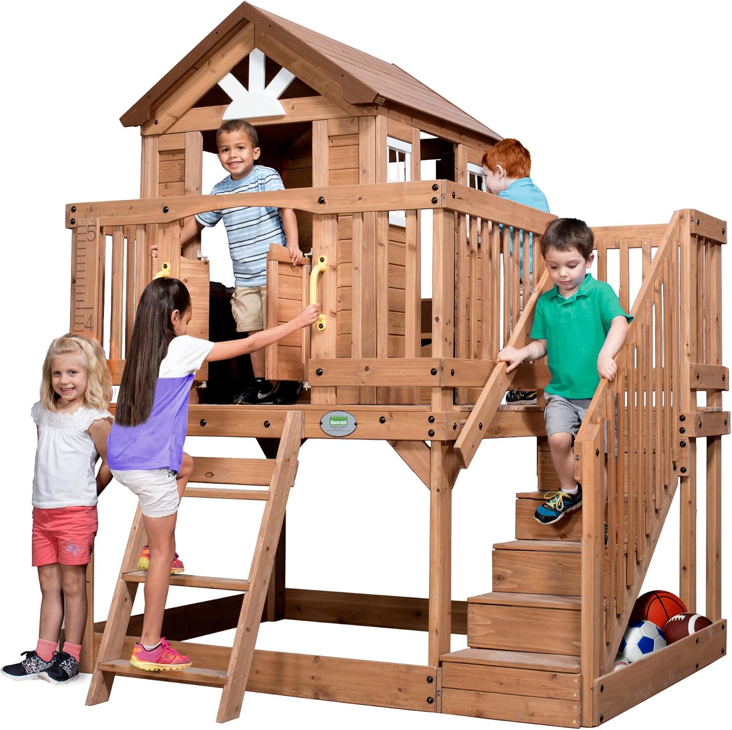 Elevated cedar wooden playhouse with integrated play kitchen, wrap-around deck, and saloon-style doors for outdoor play — front