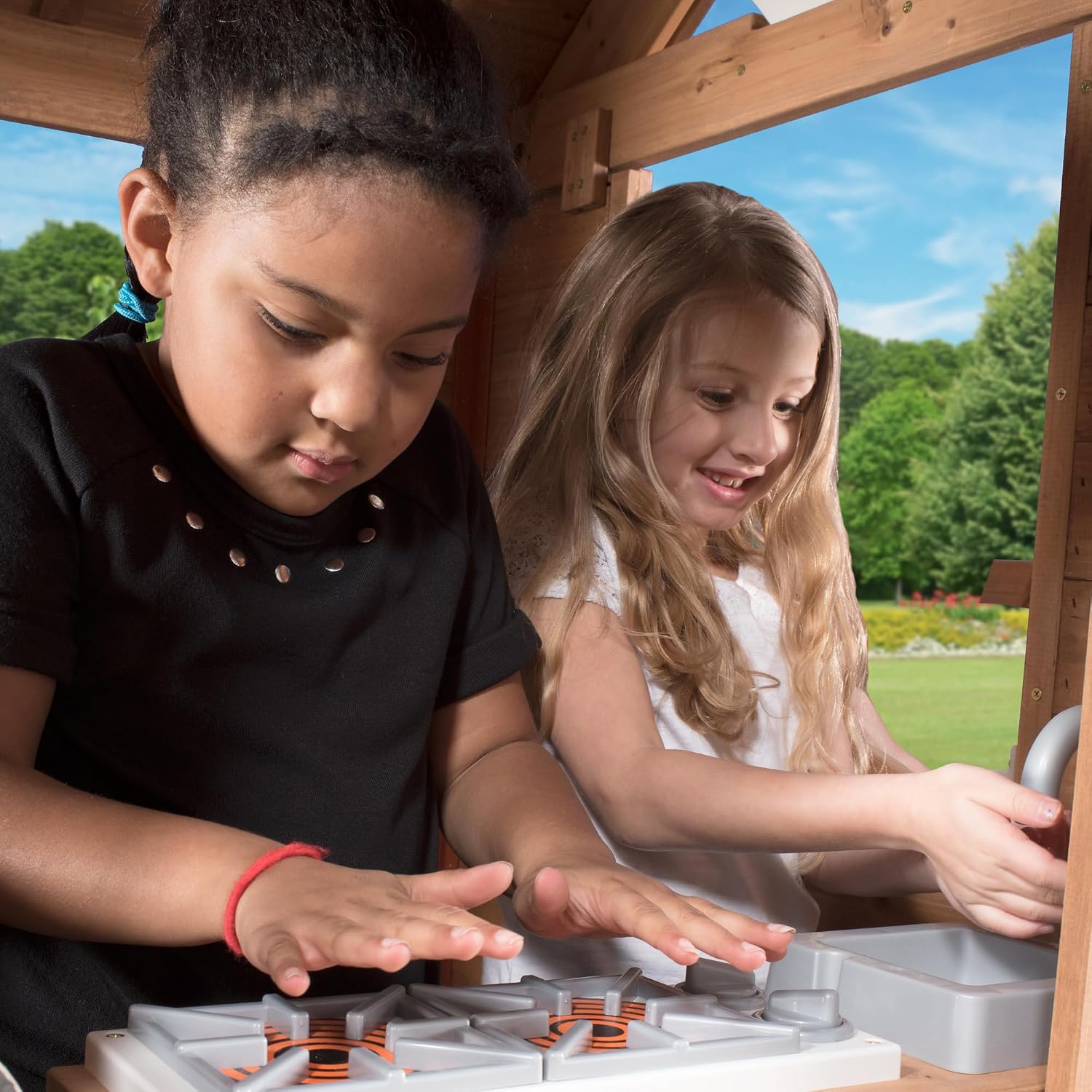 Elevated cedar wooden playhouse with integrated play kitchen, wrap-around deck, and saloon-style doors for outdoor play — view 3