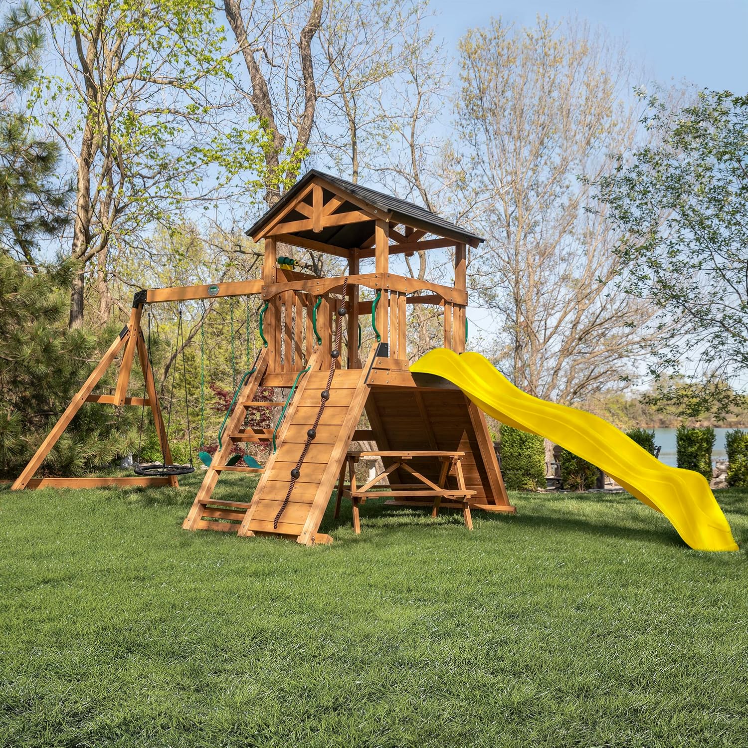 Cedar wood outdoor swing set with integrated wave slide, double rock wall, web swing, and elevated play deck for children ages 3-8 — view 1