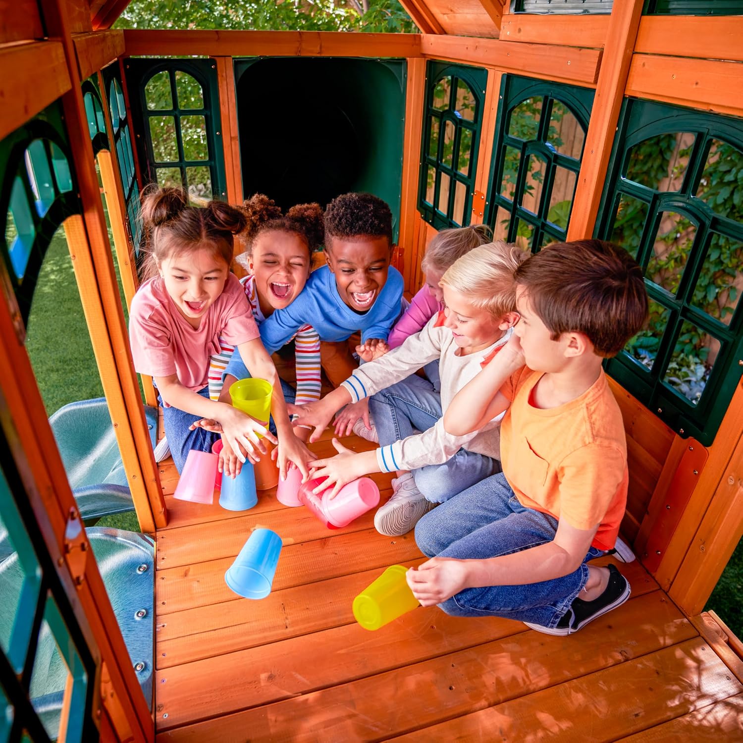 Wooden outdoor swing set with three slides, climbing wall, glider, and integrated play kitchen with cafe window for preschoolers — view 2