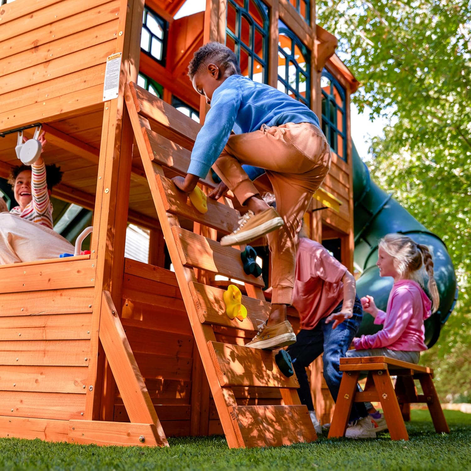 Wooden outdoor swing set with three slides, climbing wall, glider, and integrated play kitchen with cafe window for preschoolers — view 3